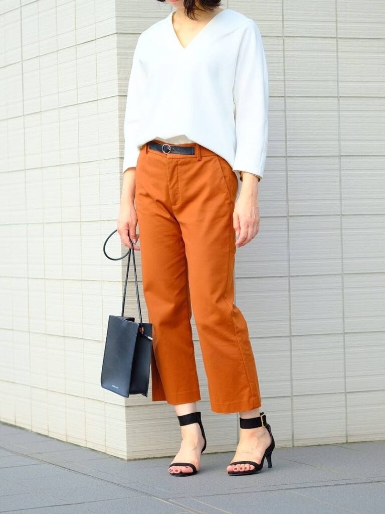 女性 白シャツ オレンジのパンツ 黒いバッグ