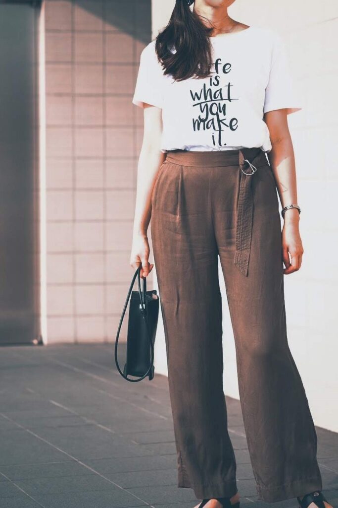 女性 白いTシャツ 茶色いワイドパンツ 黒いバッグ