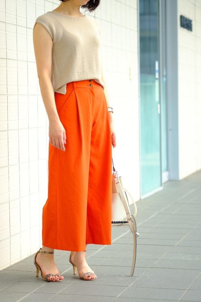 女性 ベージュのトップス オレンジのパンツ サンダル